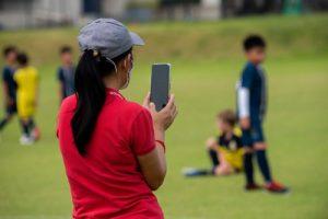 Mom using phone to record youth soccer game.