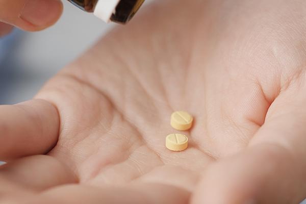 Close up of two yellow pills on a hand.
