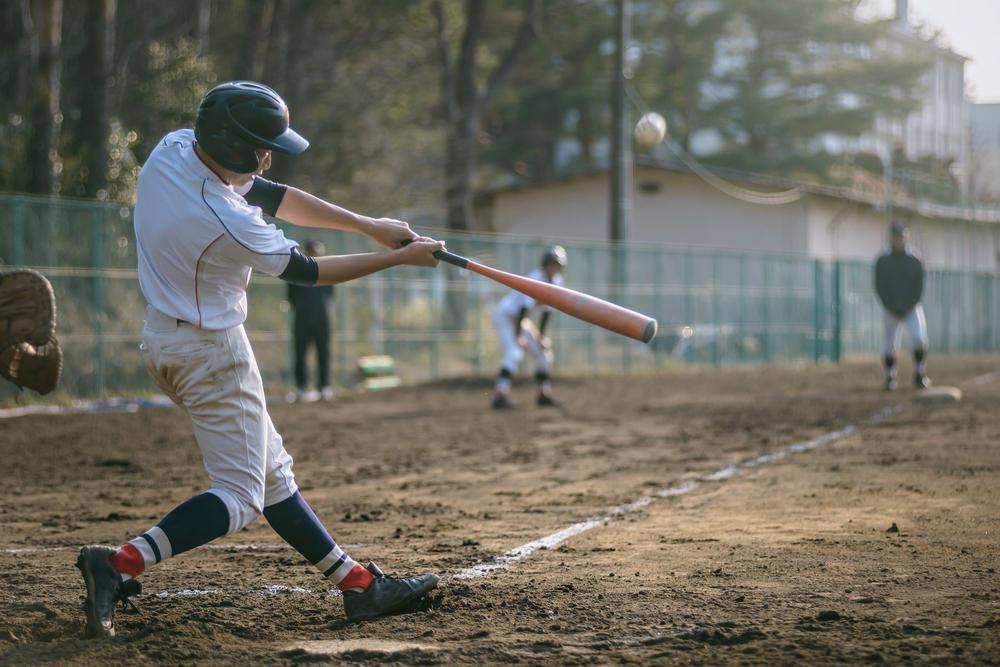 Teen hitting baseball during game.