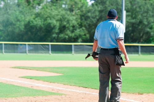 An umpire standing alone on a baseball diamond.