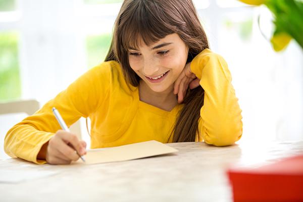 Young girl writing a letter at a desk.