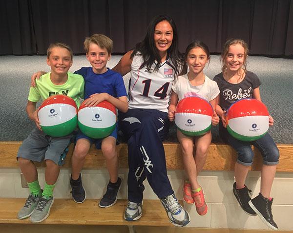 Candace Vering sitting with children holding TrueSport beachballs