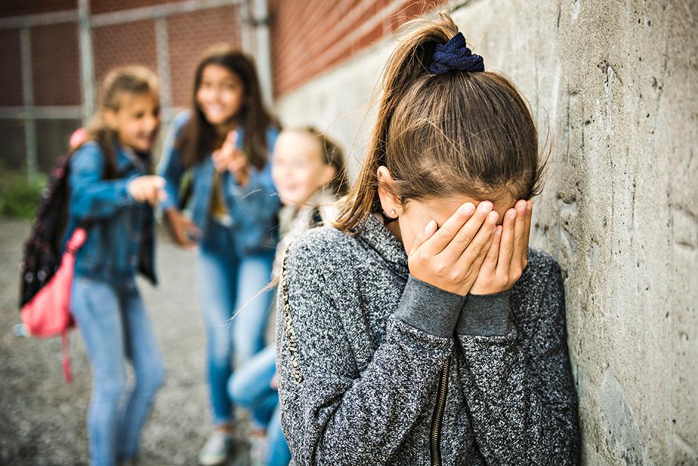 Young girl being bullied by three other girls.