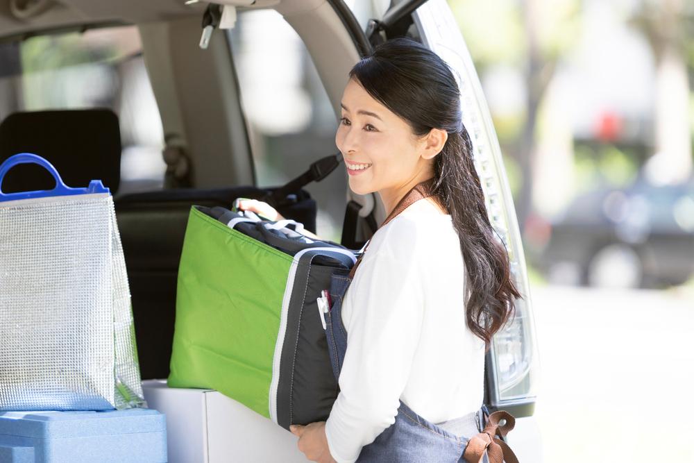 Asian woman taking a cooler out of a van.