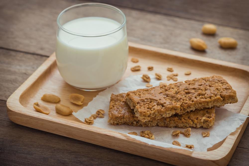 Granola bar next to a glass of milk.