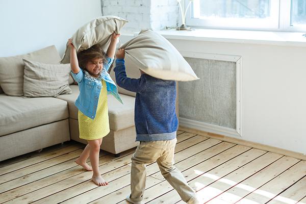 A boy and girl sibling having a fun pillow fight.