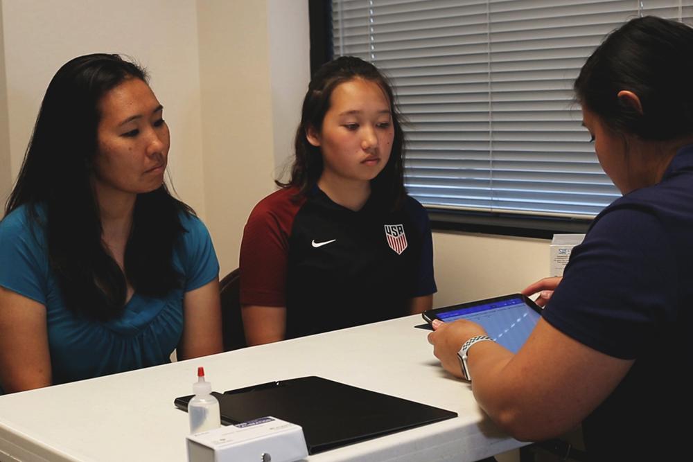 Parent and youth athlete sitting with an doping control officer.