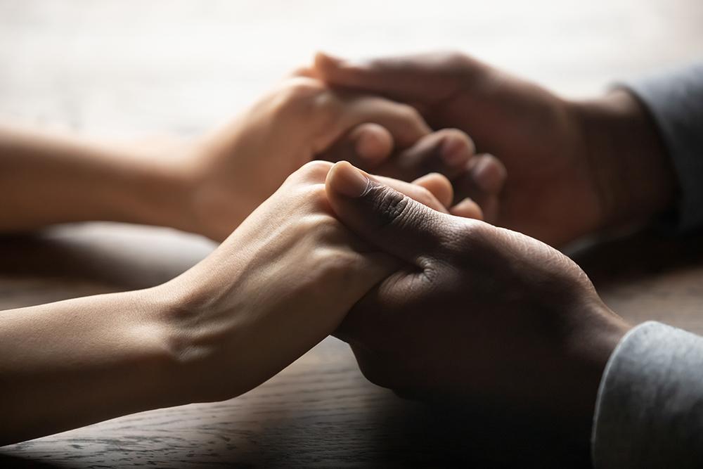 Close up of two people holding hands.