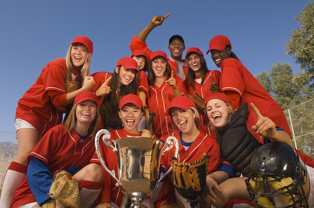 Softball team celebrating a win with coach.