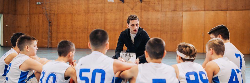 Coach talking to young men's basketball team.