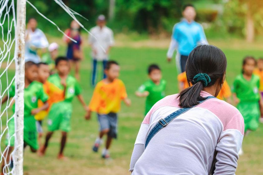 Woman yelling on youth soccer game sidelines.