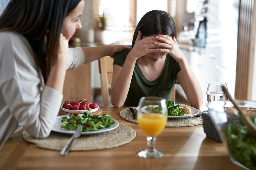 Parent consoling daughter over a meal.