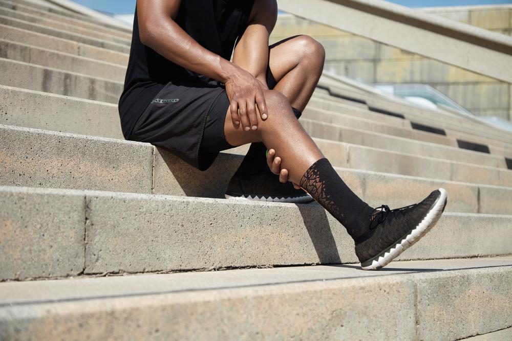 Young man holding knee sitting on concrete steps.