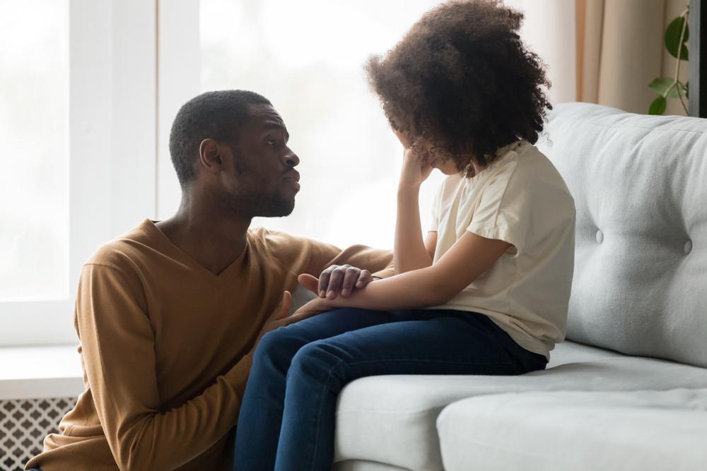 Father comforting daughter on couch.
