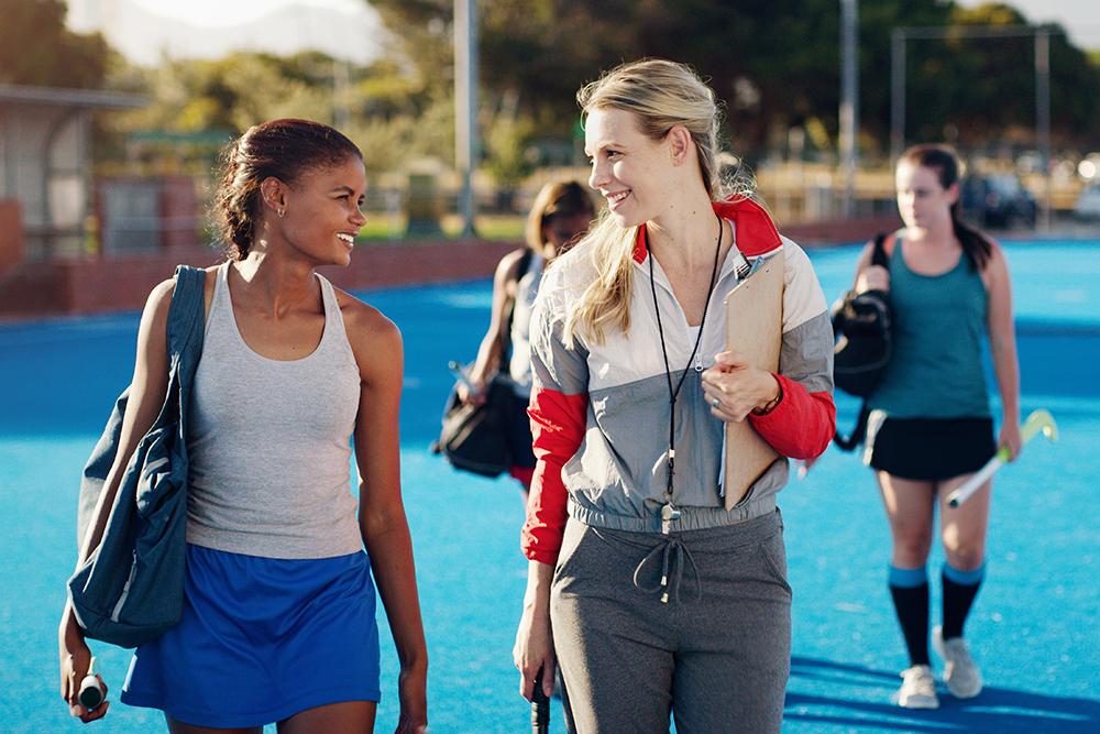 Female coach talking to field hockey athletes.