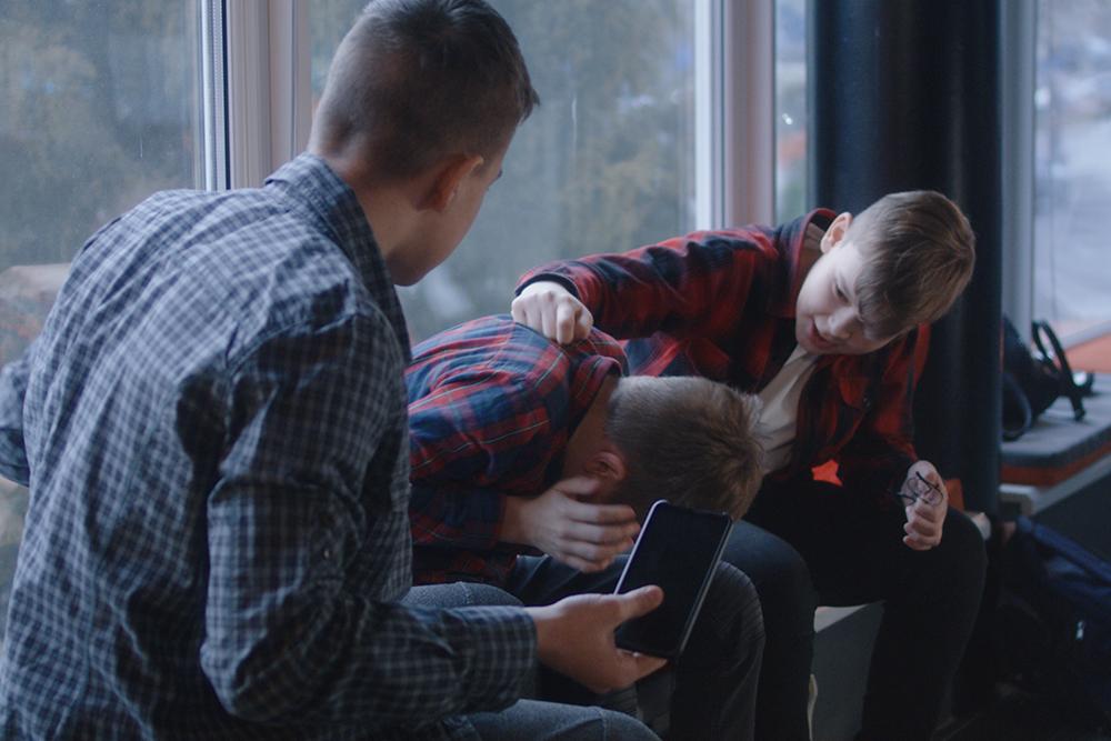 Teen boy comforting friend as another boy bullies him.