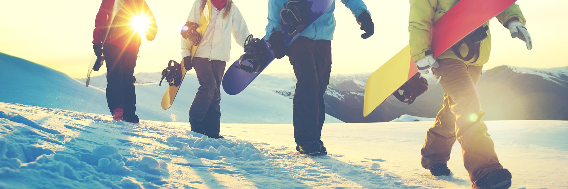 Snowboarders walking on snow.