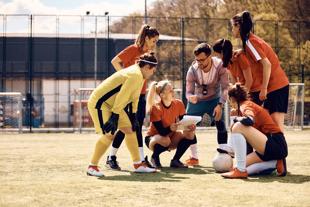 Young coach with girls field hockey team.