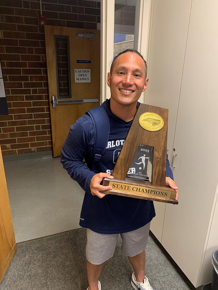 Coach Powell Paguibitan holding a championship trophy.