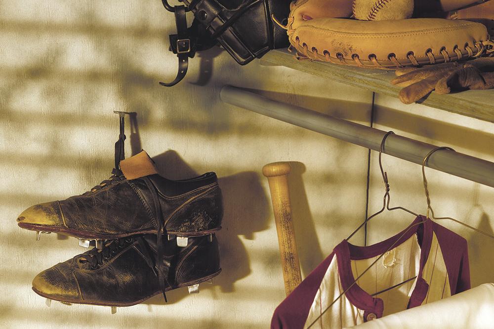 Baseball cleats and other gear hanging in a closet.