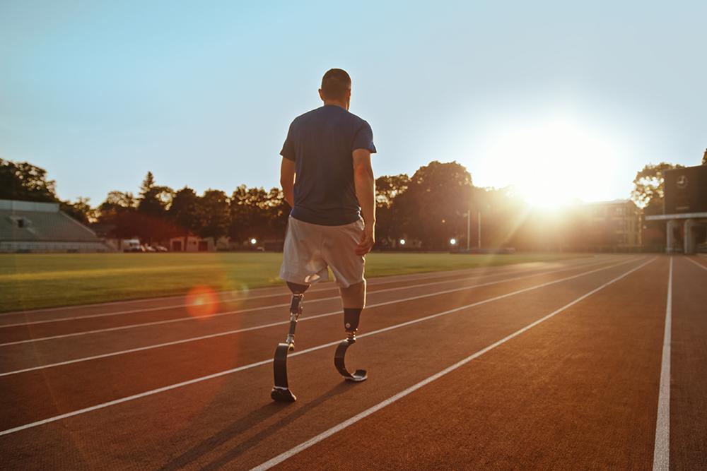 Male athlete double amputee standing on track.