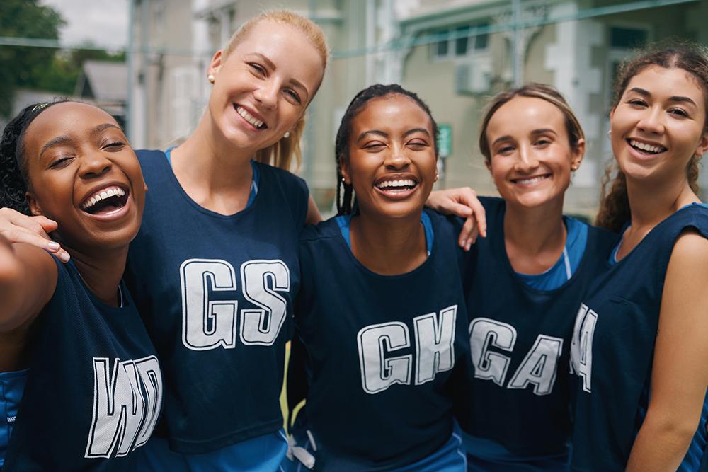 Diverse group of teenage girls smiling in sport uniforms.
