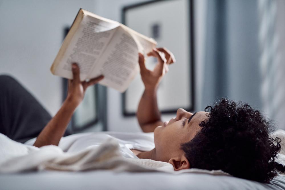 Young man reading a book while laying down,.