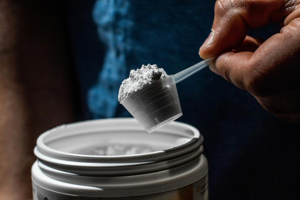 Close up of a supplement powder being scooped out of a container.
