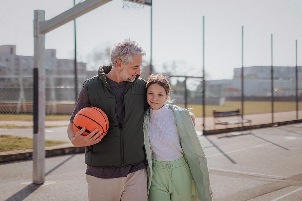 Father with daughter on basketball court.