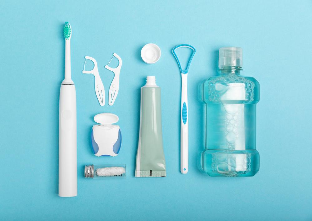 Oral hygiene items including toothbrush, floss, and mouthwash against blue background.