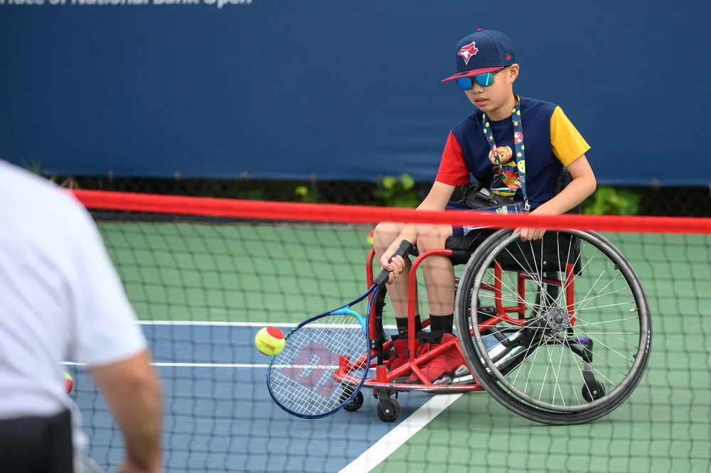 Young mane in a wheelchair playing tennis.
