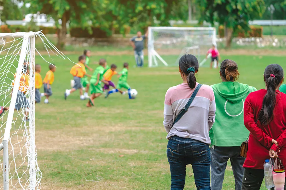 Parents on sideline at a youth soccer game.