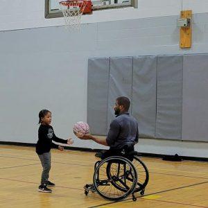 Trey Jenifer and child playing basketball.