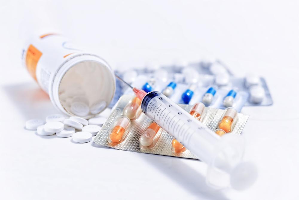 Pills and a syringe on a white background.