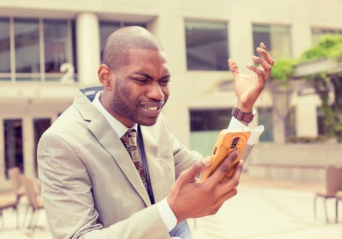 Angry man looking at cell phone.