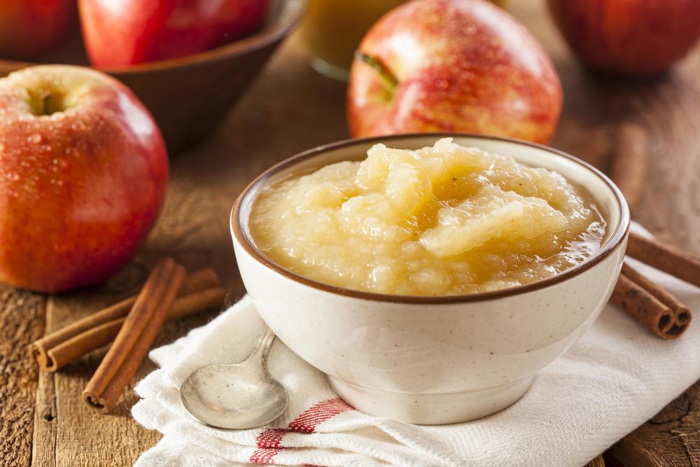 Applesauce in a cup in front of apples.