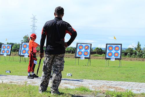 Archery coach watching young archer.