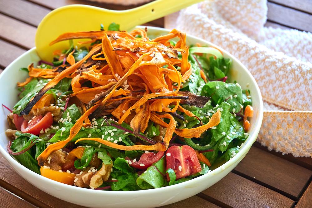 Big bowl of salad with shaved carrots on top.