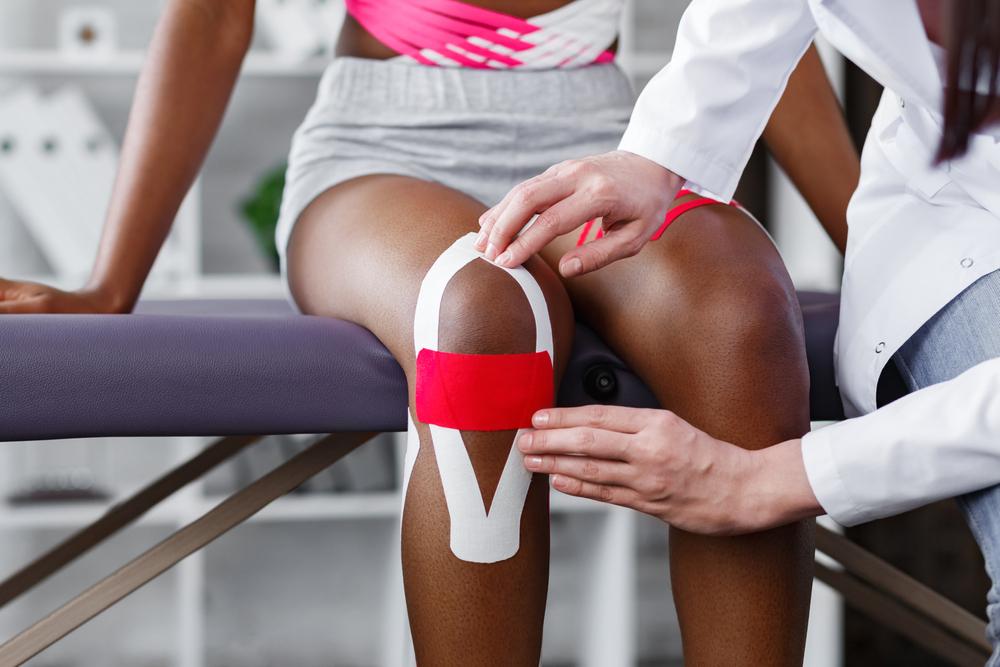 Trainer taping an athlete's knee.