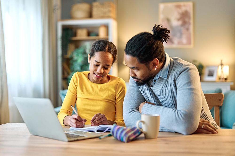 Dad helping daughter with writing.