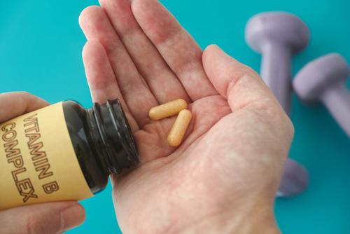 A hand holding b vitamin supplements.