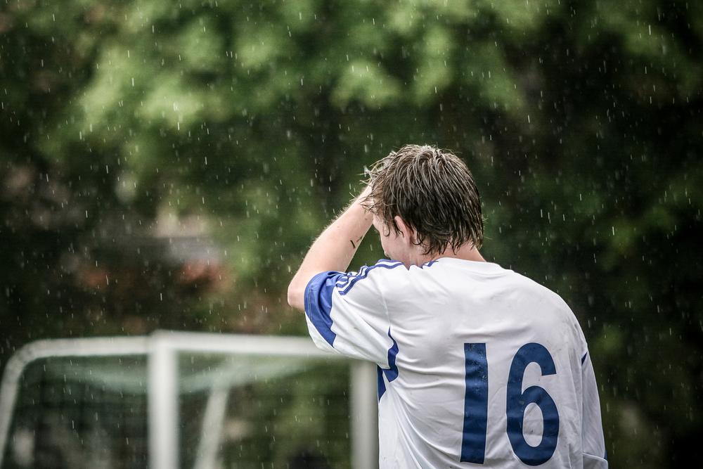 Football player standing alone in the rain.