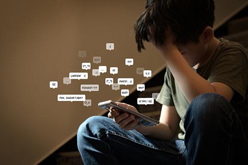 Boy on phone with icons of negative messages from social media.