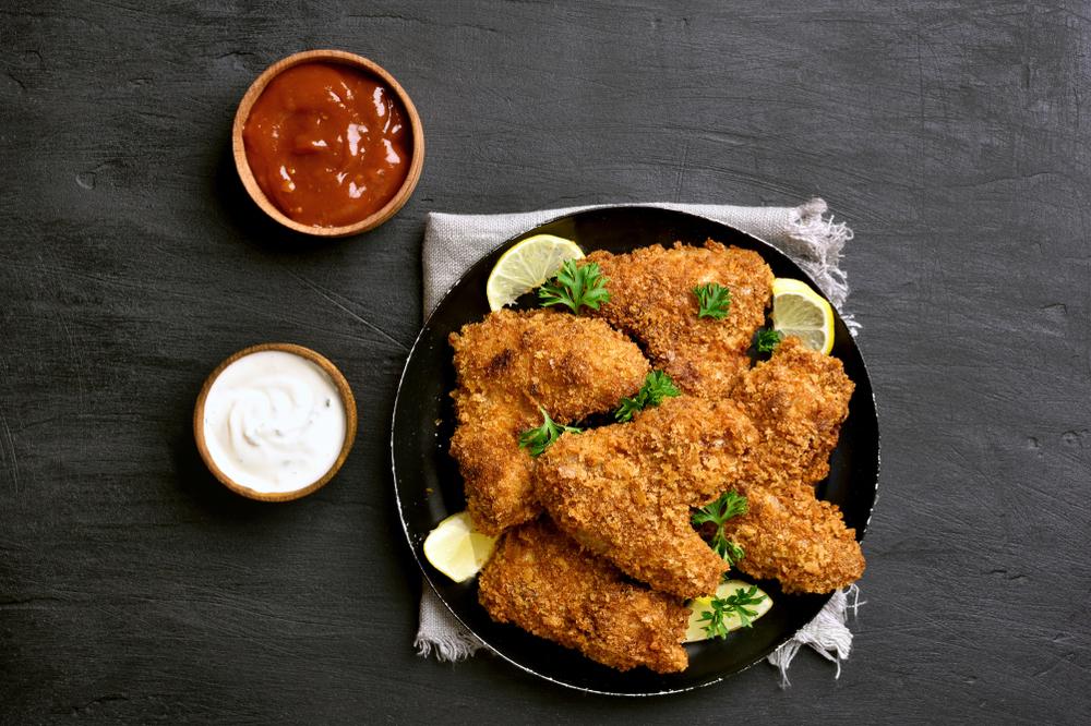 Baked fried chicken on a plate with two dipping sauces.