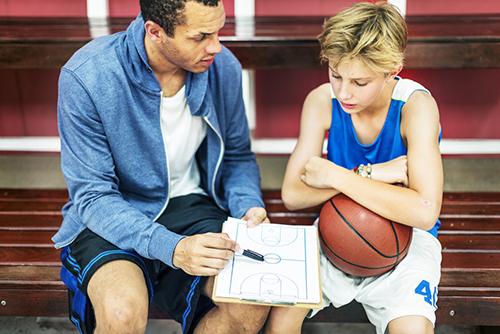 Basketball coach talking one on one to male player.