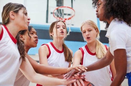 Female coach hyping up young female basketball team.