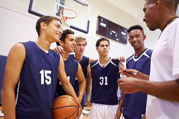 Coach talking to teen male basketball team.