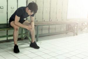 Young asian man sitting alone in locker room.