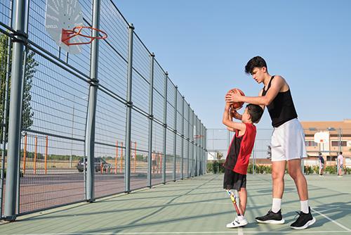 Young boy with prothesis coached in basketball.