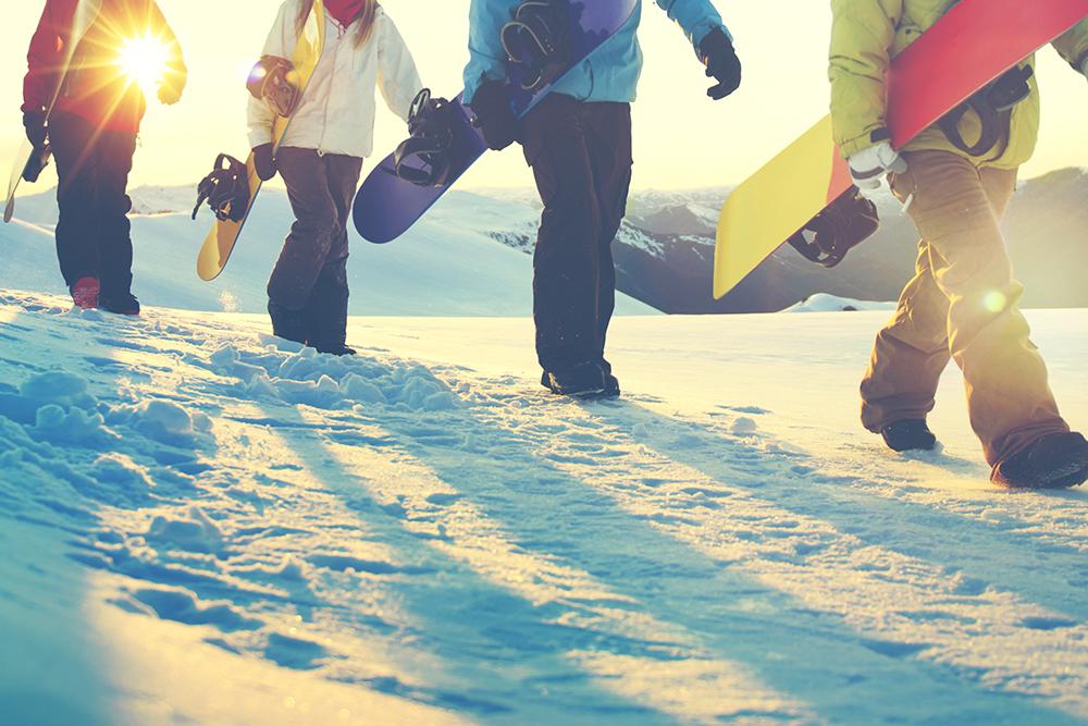 Snowboarders walking on snow.